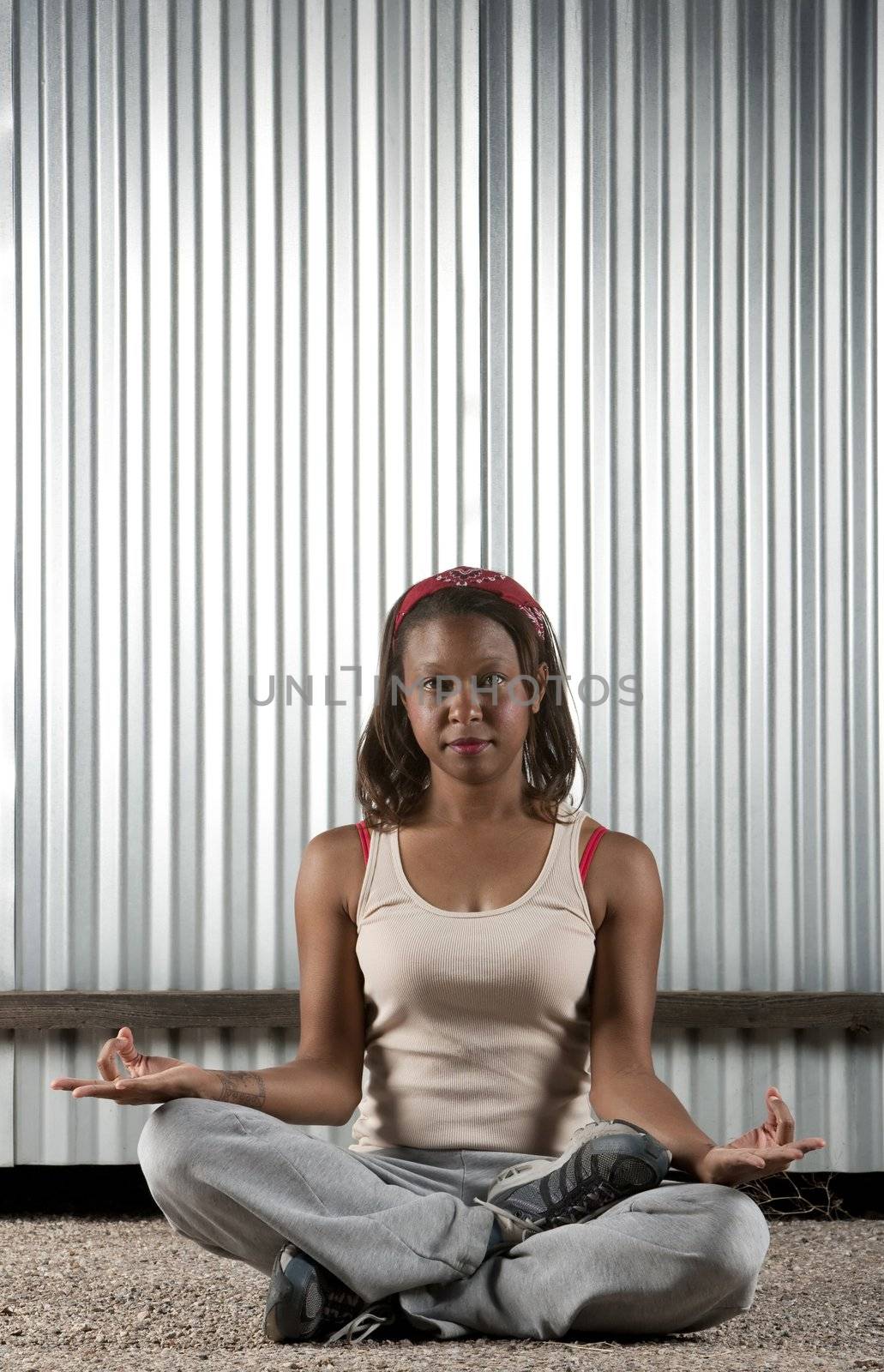 African-American woman meditating in front of corrugated metal