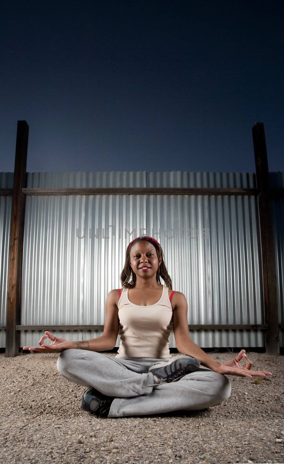 African-American woman meditating in front of corrugated metal