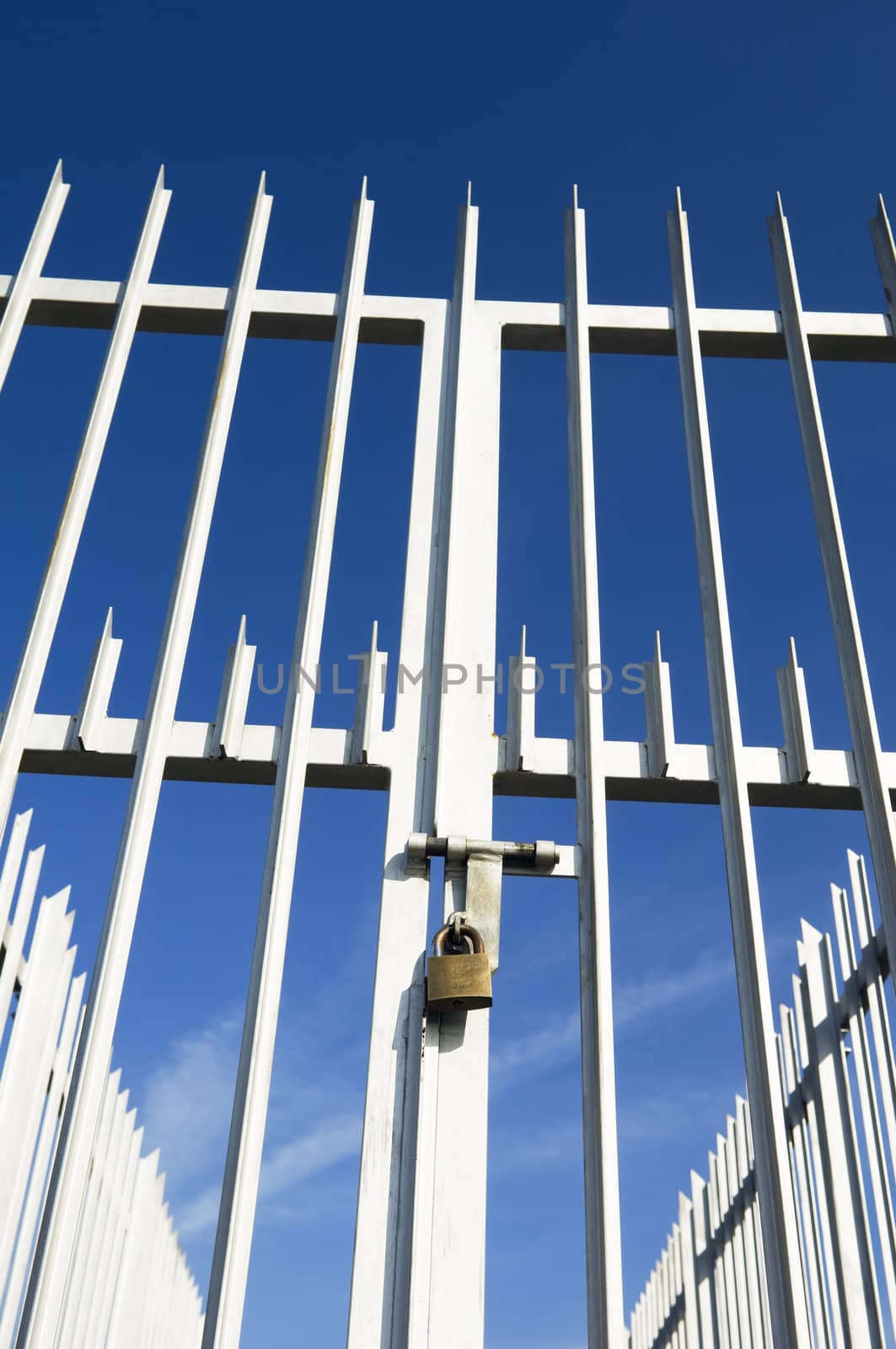 Modern spiked fence and gate closed with a padlock