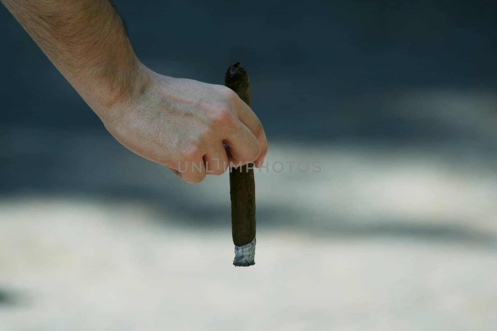 A Hand holding a lit cigar