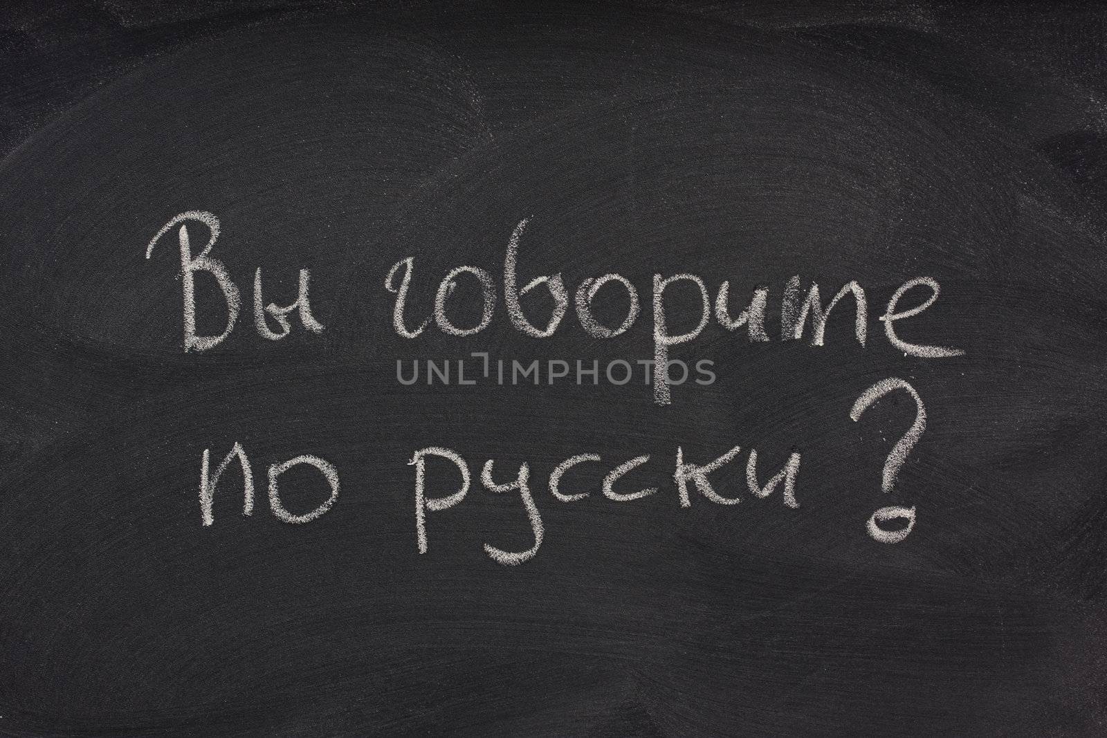 Govorite po russki? Do you speak Russian question handwritten in cyrilic alphabet with white chalk on a blackboard with eraser smudges