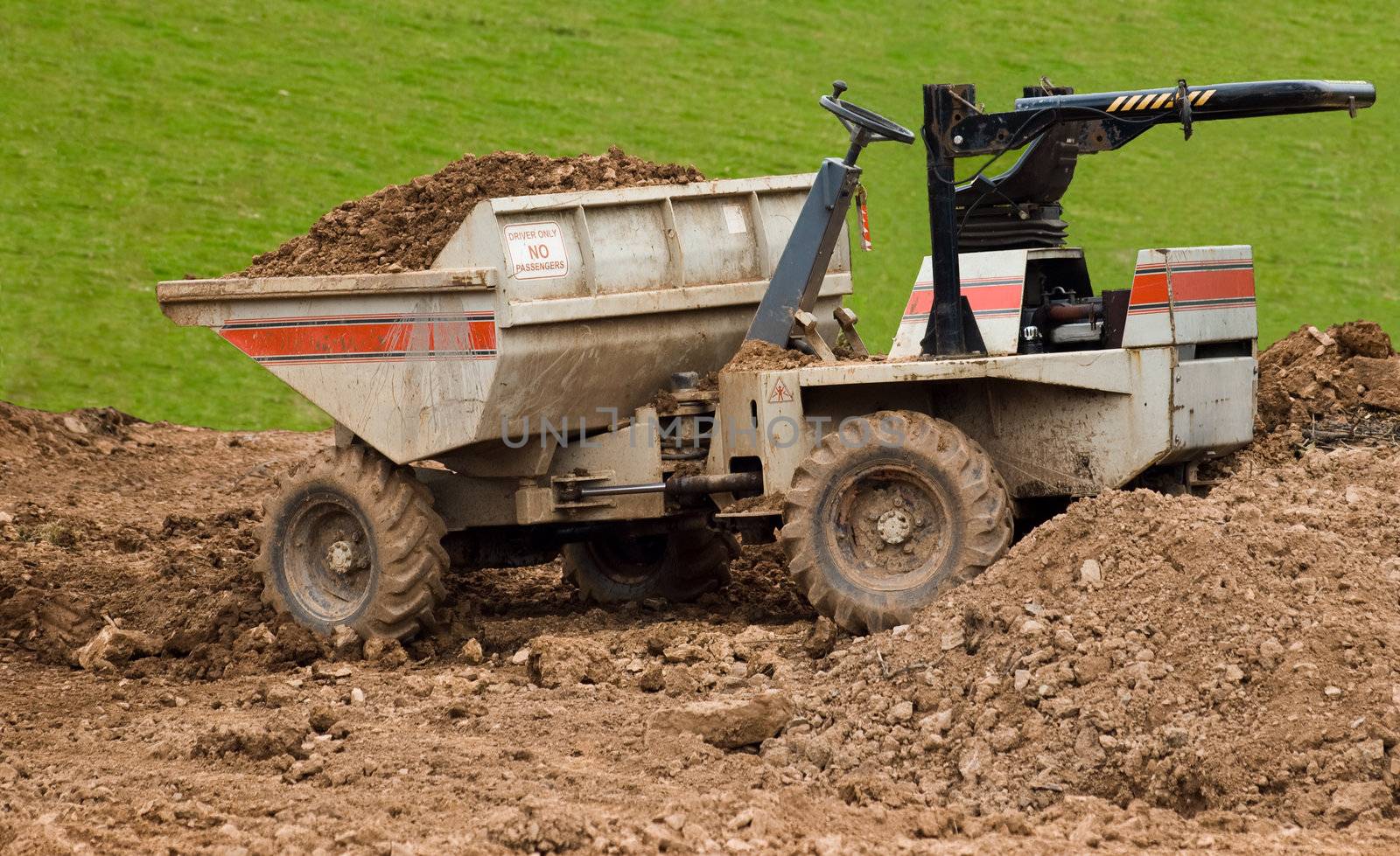 a dumper truck illegally left with its bucket full, keys in the ignition and its roll bar folded down on a building site easily accessible to the public.