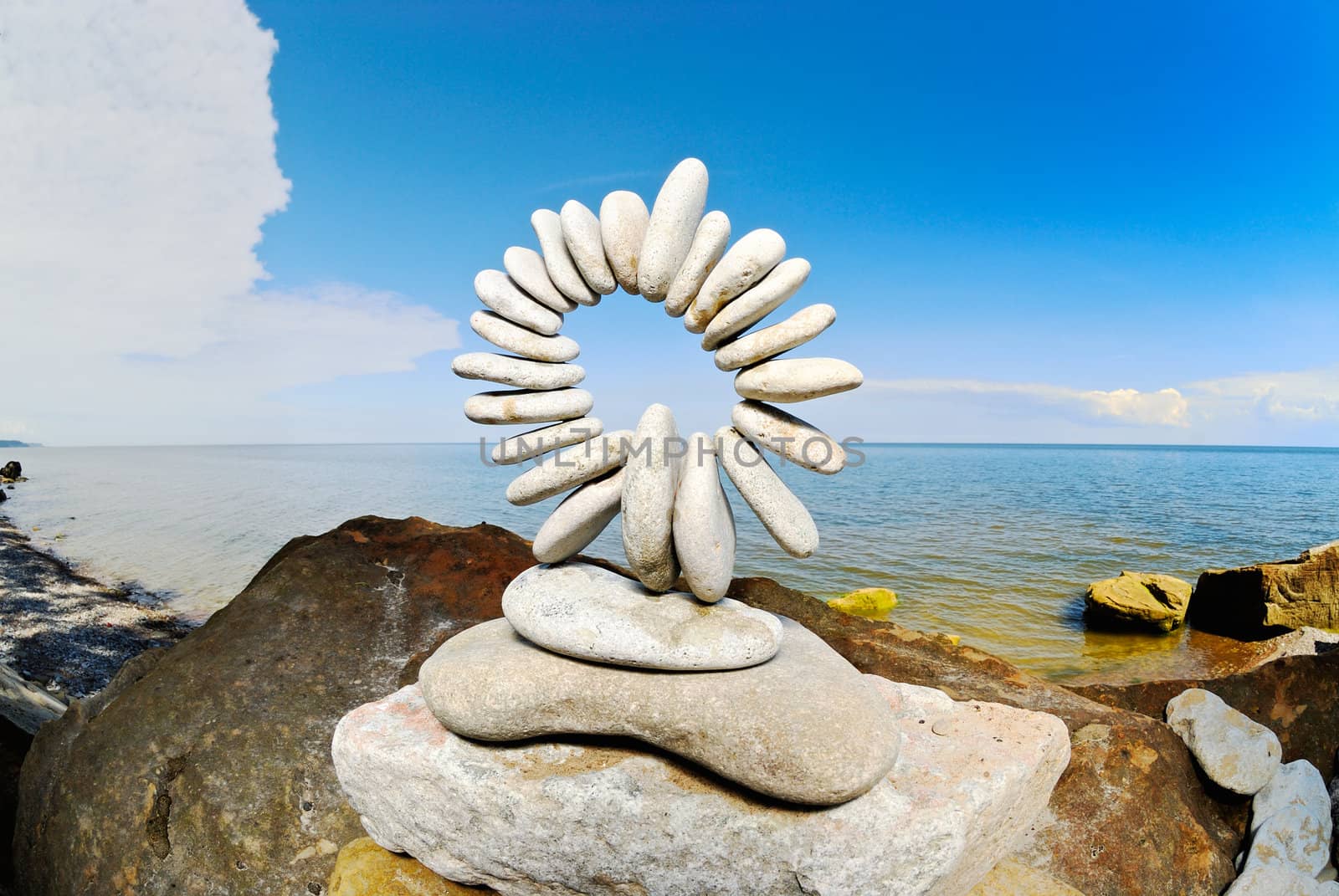 Sculptural sphere of pebbles on the sea cliff