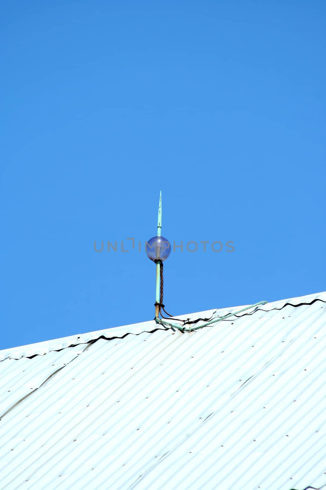 Lightning rod on top of a barn against a blue sky