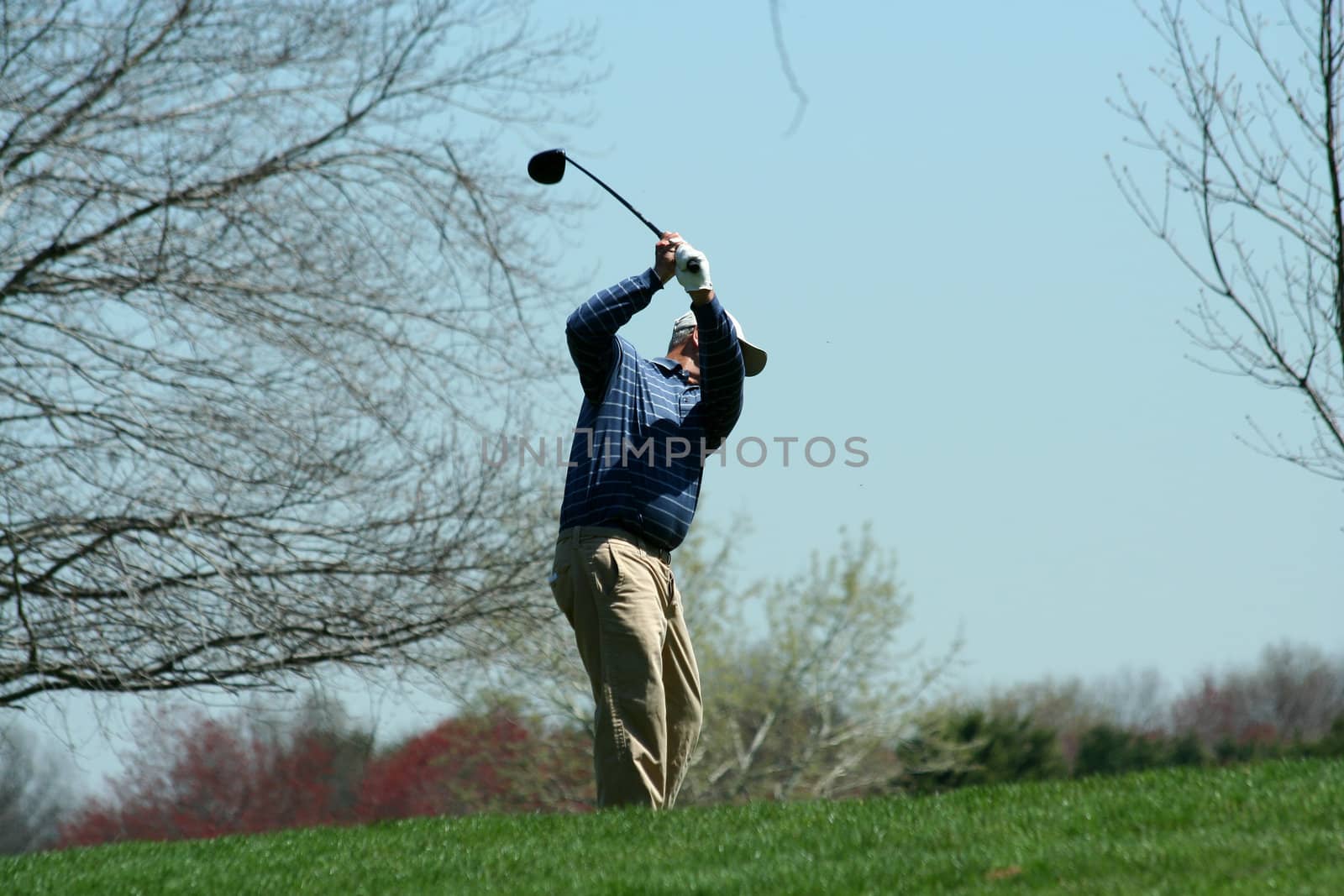 A Male golfer teeing off on a ball