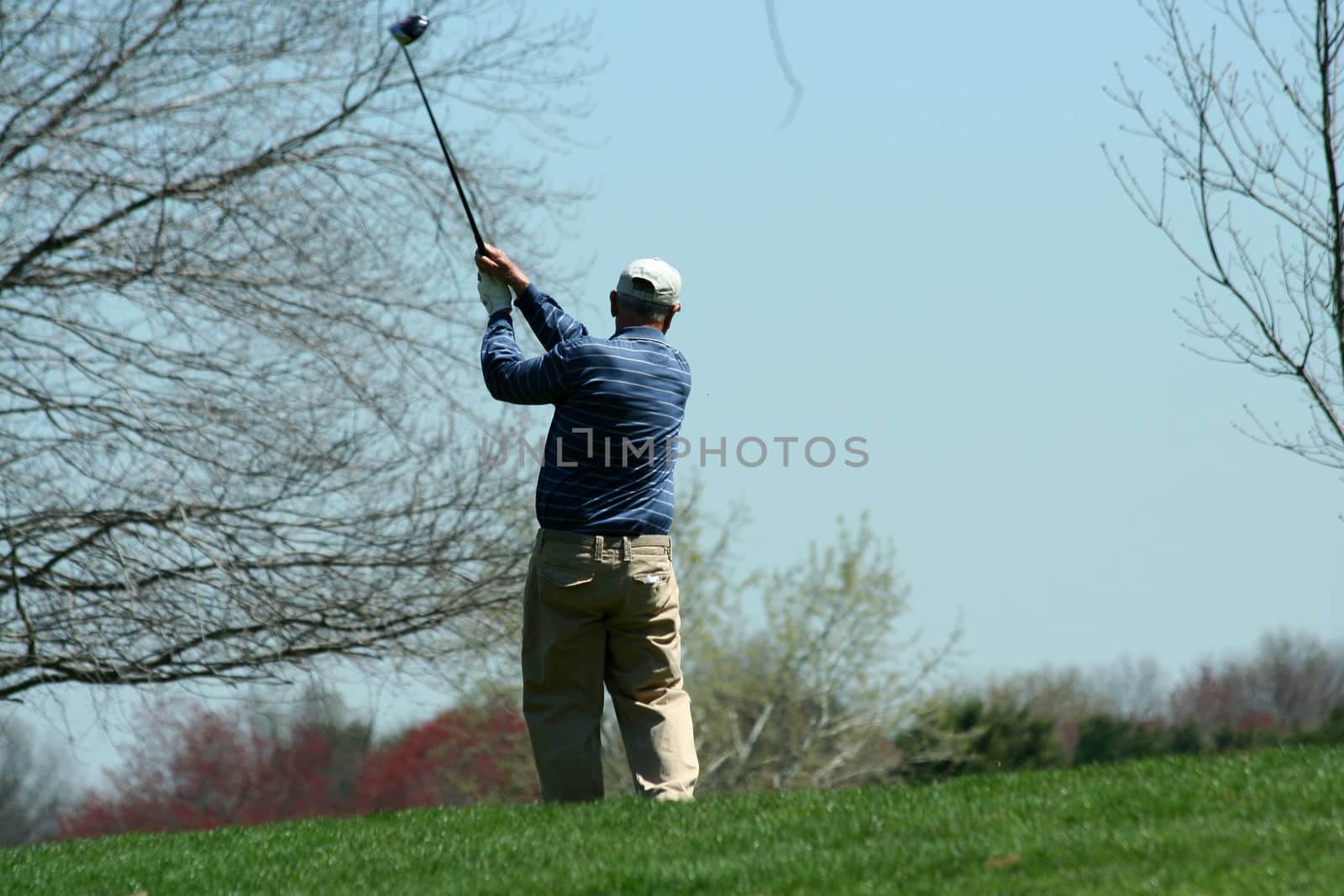 A Male golfer teeing off on a ball