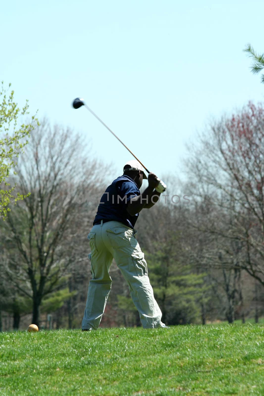 A Male golfer teeing off on a ball