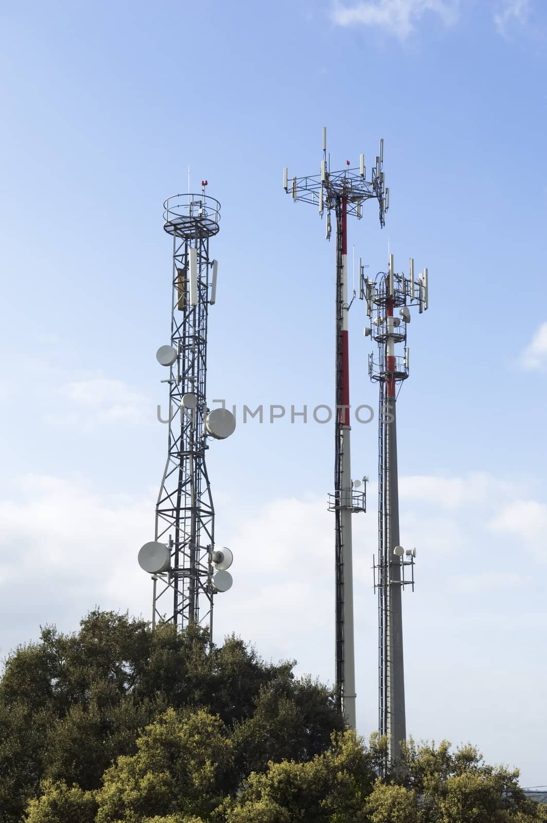 Three telecommunication antennas against a clear blue sky
