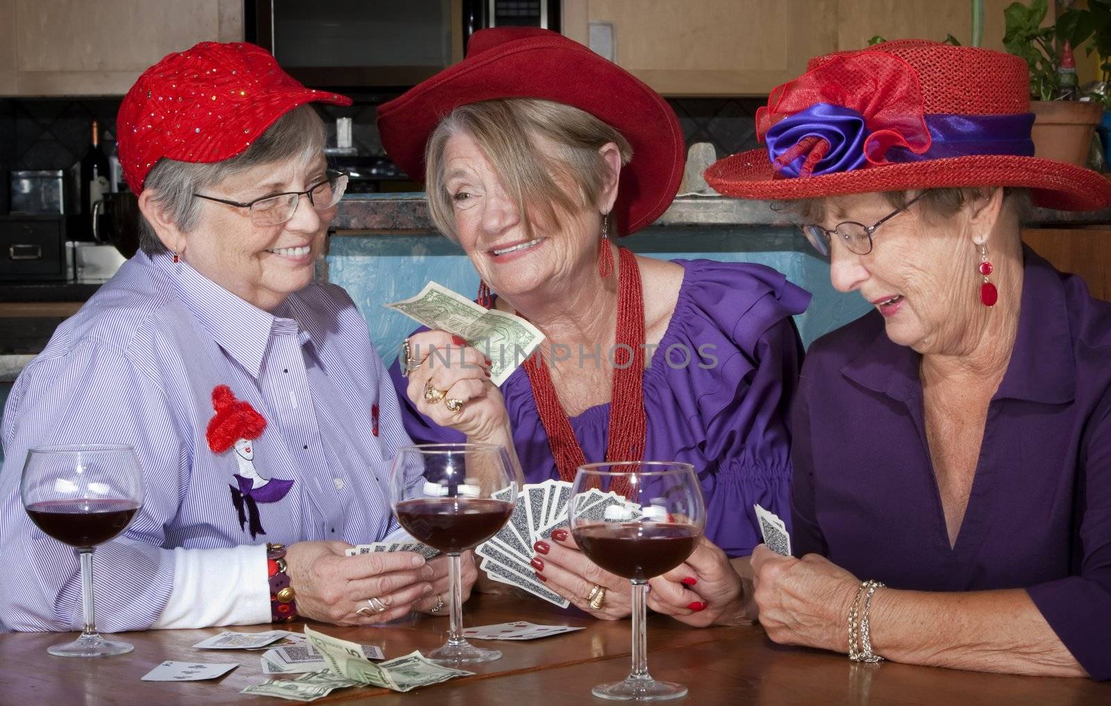 Ladies wearing red hats playing cards by Creatista