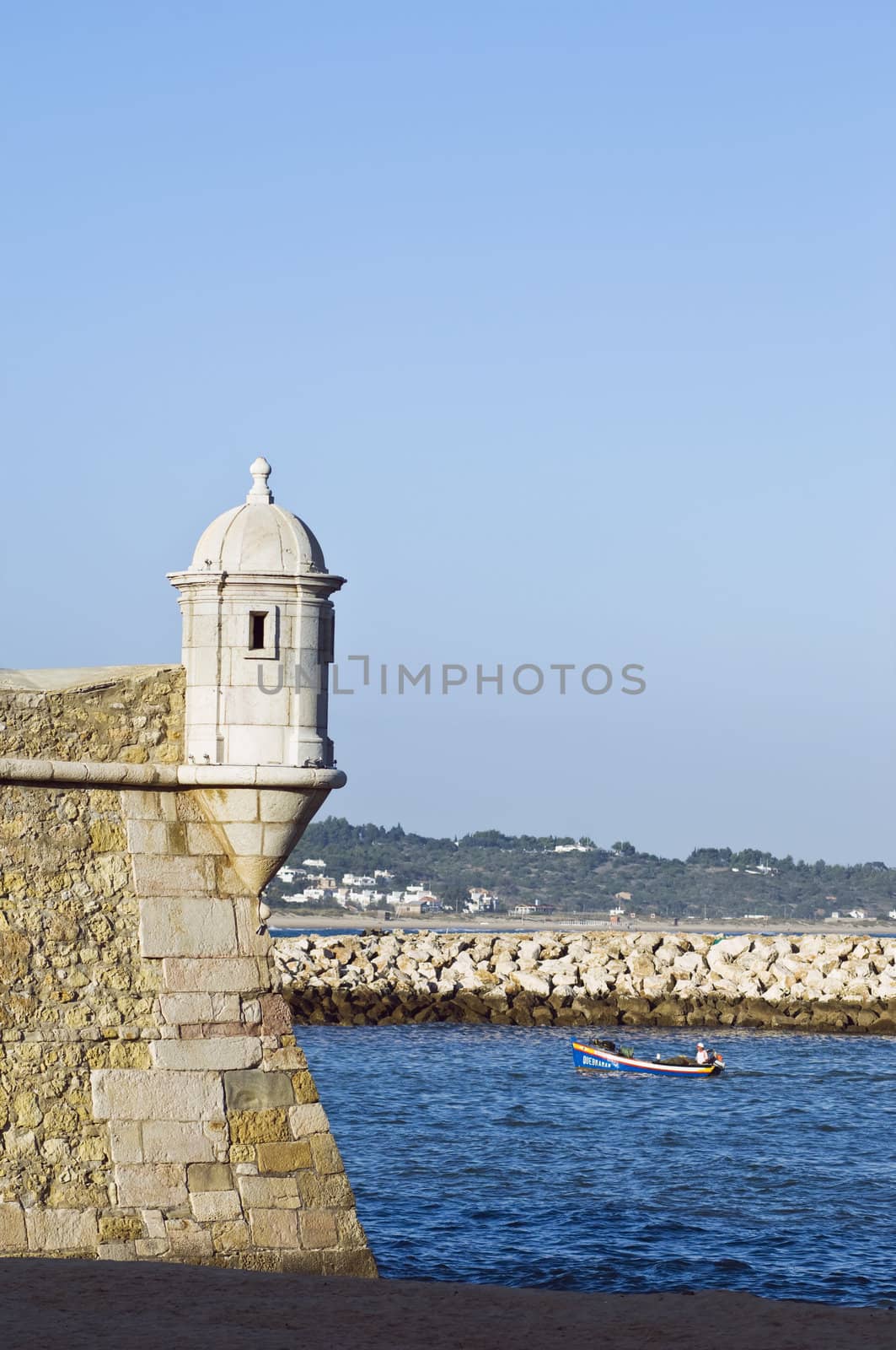 Small fishing boat entering the harbour of the historic town of Lagos, Algarve, Portugal