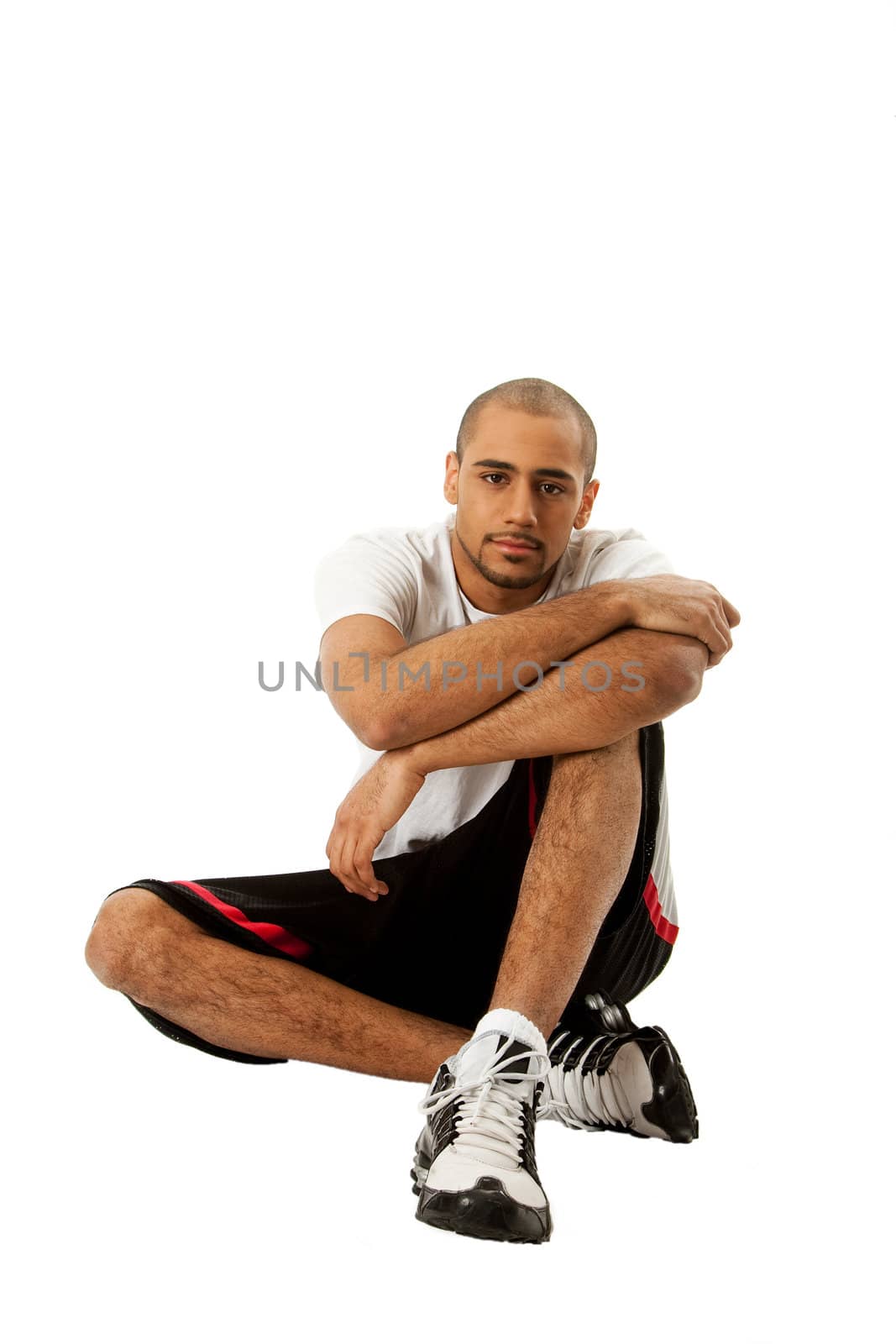 Sporty handsome African Hispanic guy sitting on floor, isolated