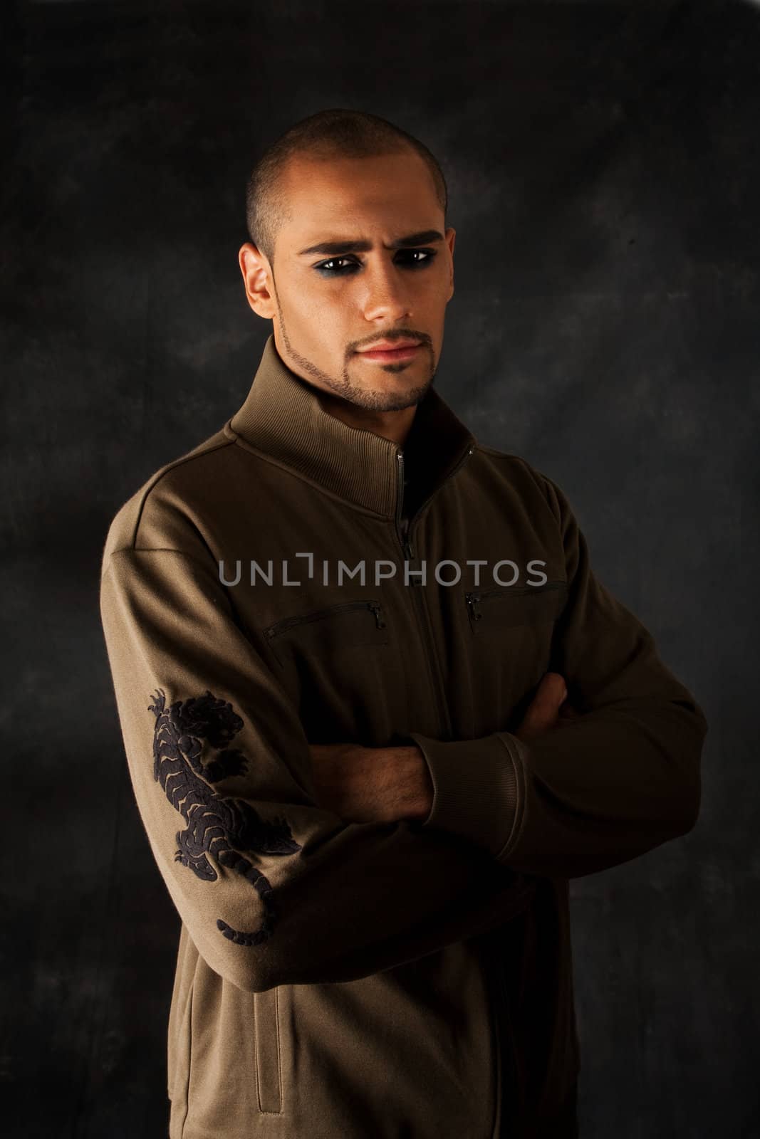 Handsome African Hispanic guy frowning with strong macho expression and dark eyes in green vest with black tiger on sleeve