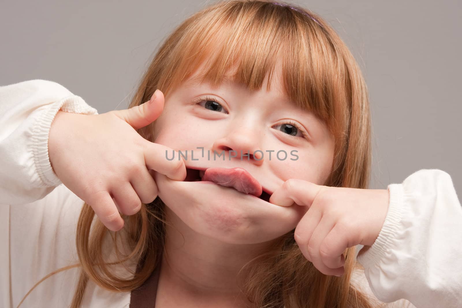 Portrait of an Adorable Red Haired Girl on a Grey Background.