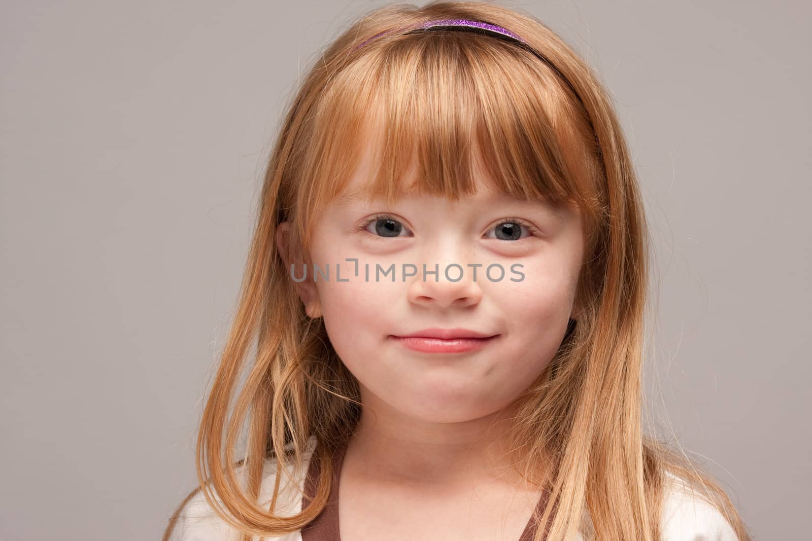 Portrait of an Adorable Red Haired Girl on a Grey Background.