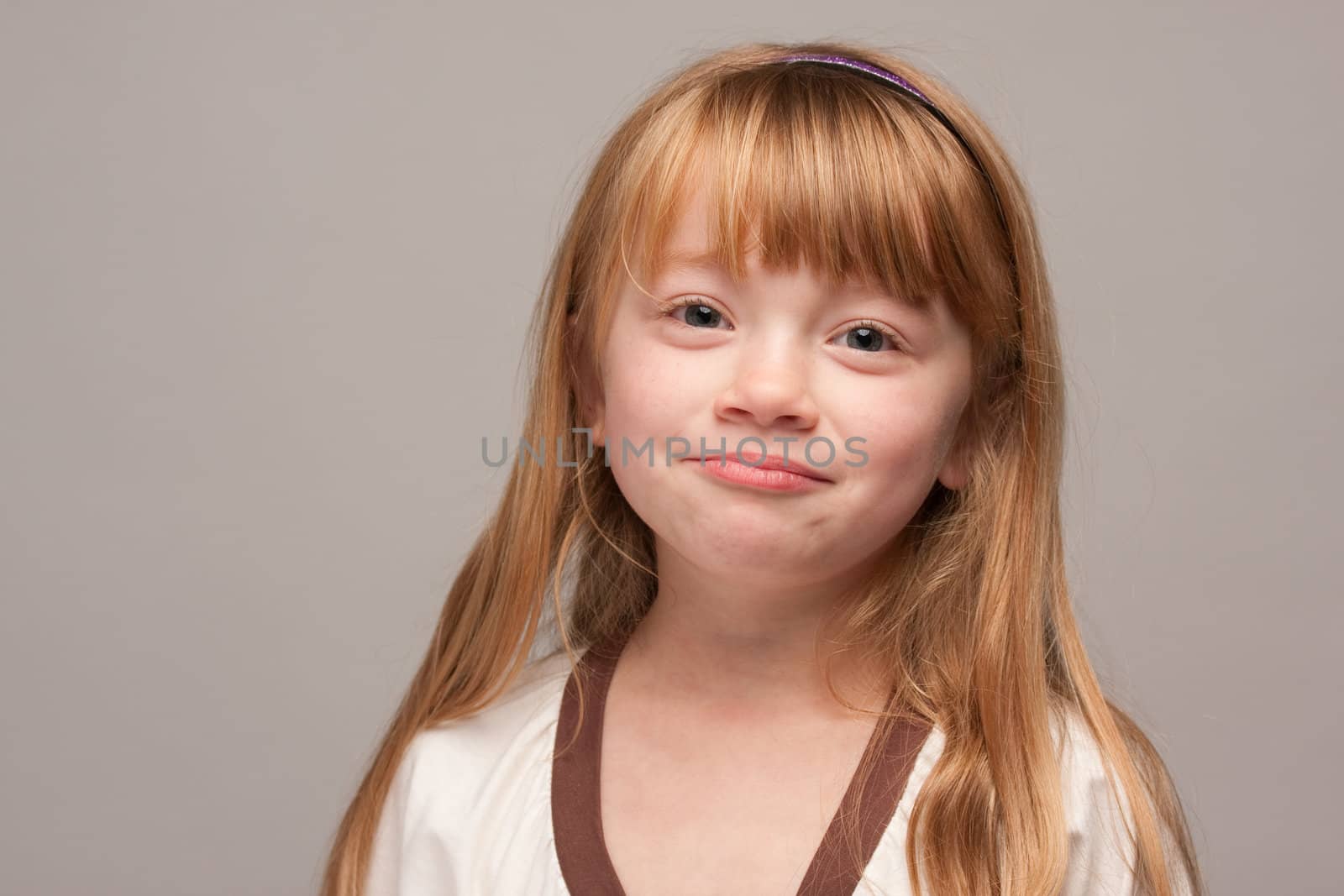 Portrait of an Adorable Red Haired Girl on a Grey Background.