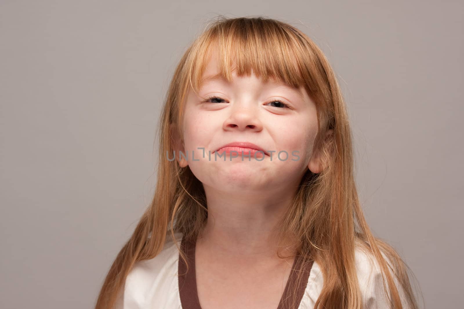 Portrait of an Adorable Red Haired Girl on a Grey Background.