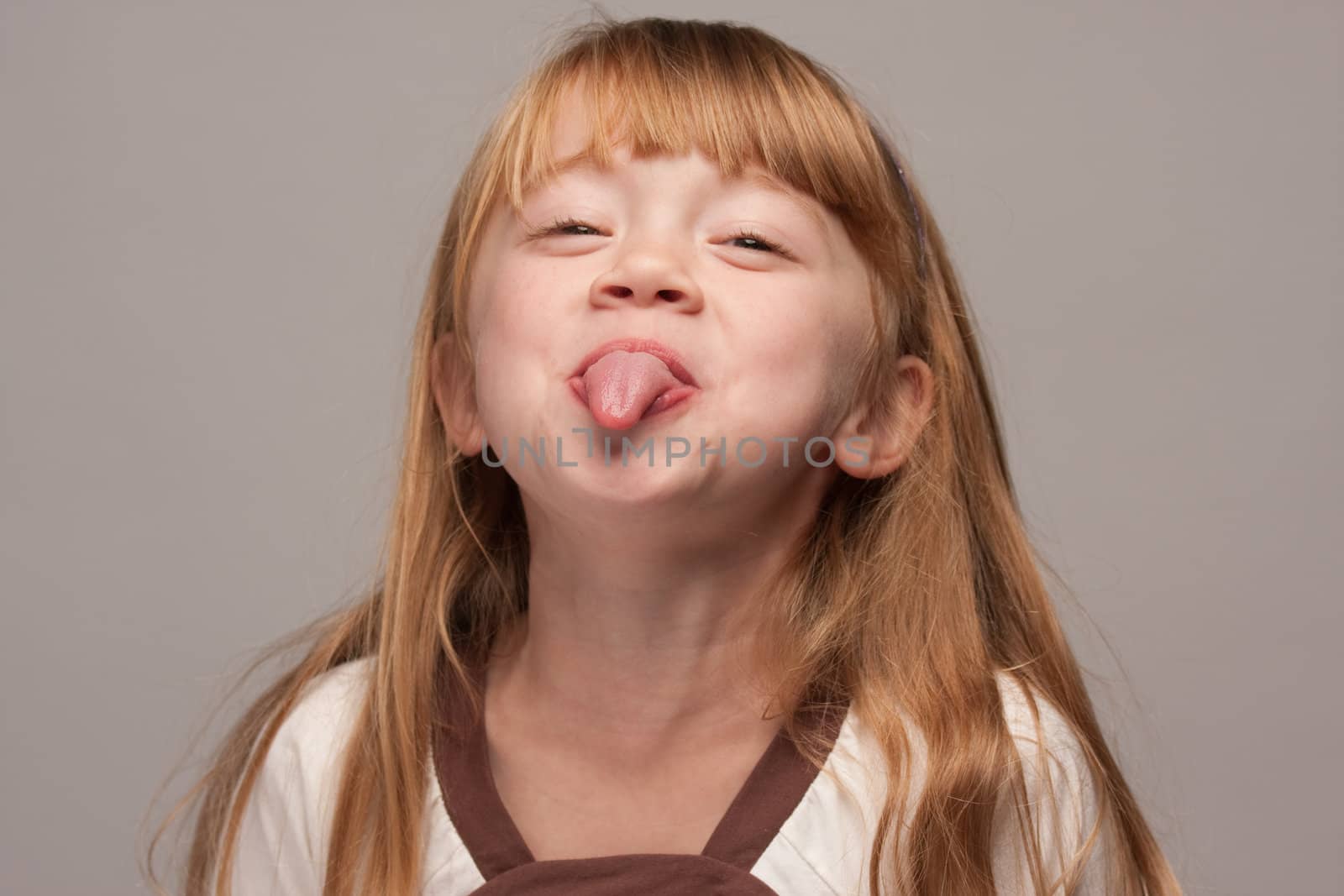 Portrait of an Adorable Red Haired Girl on a Grey Background.