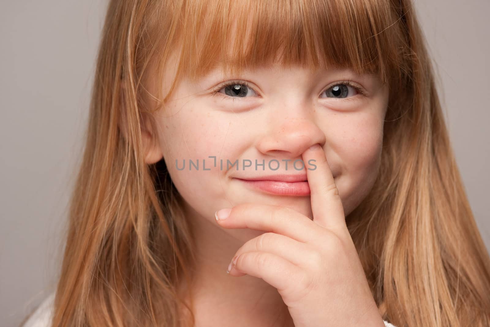 Portrait of an Adorable Red Haired Girl on a Grey Background.