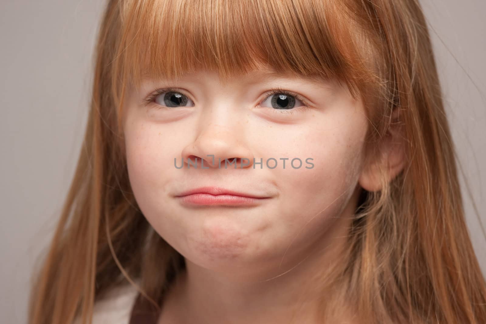 Portrait of an Adorable Red Haired Girl on a Grey Background.