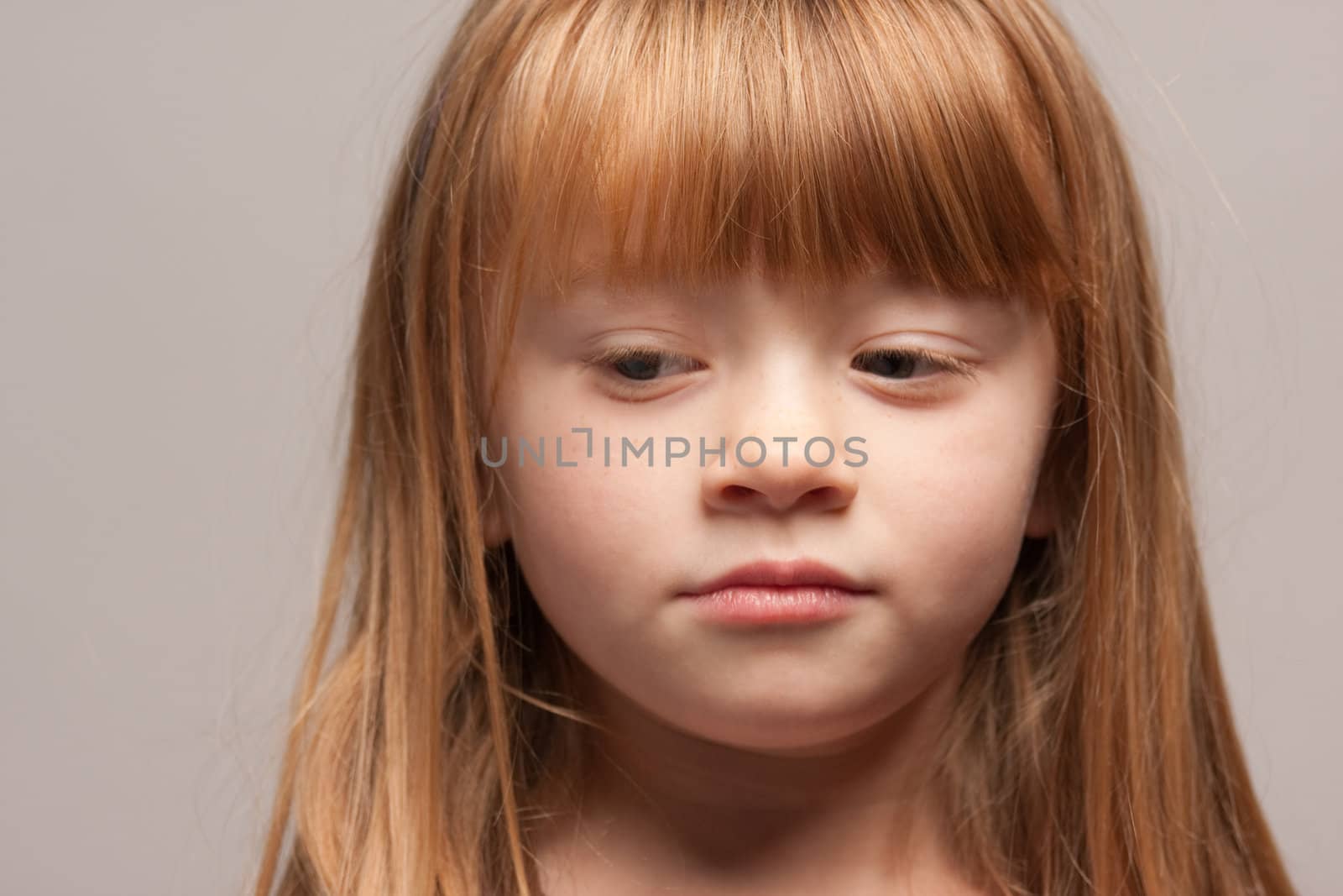 Portrait of an Adorable Red Haired Girl on a Grey Background.