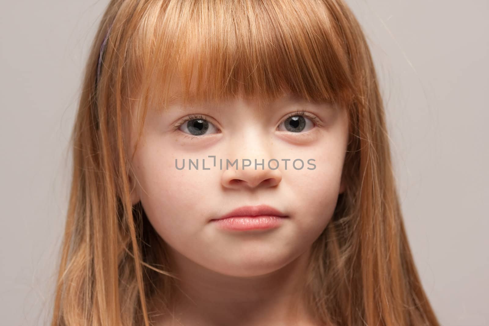 Portrait of an Adorable Red Haired Girl on a Grey Background.