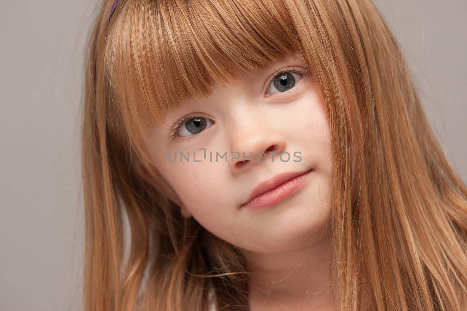 Portrait of an Adorable Red Haired Girl on a Grey Background.