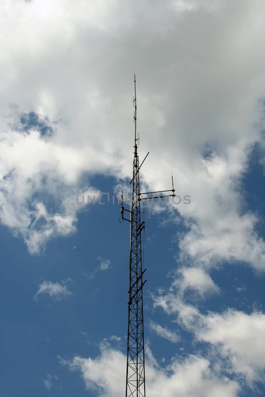 A Radio antenna against a cloudy blue sky