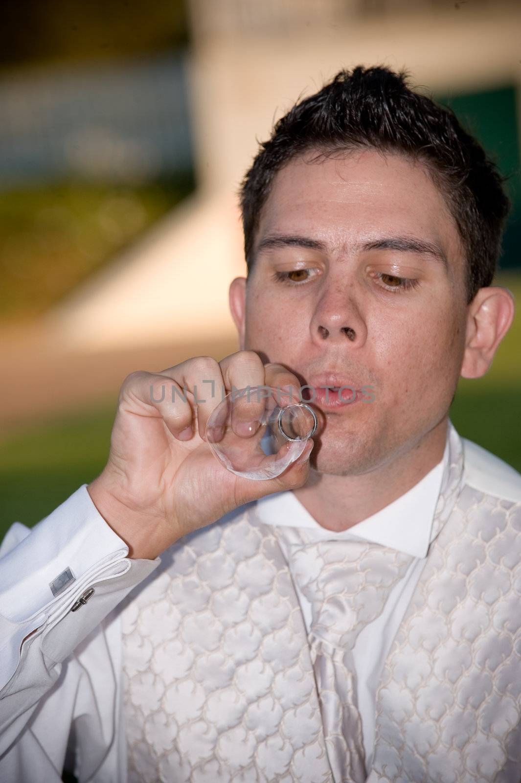 well dressed groom blowing bubbles through a wedding ring by Ansunette