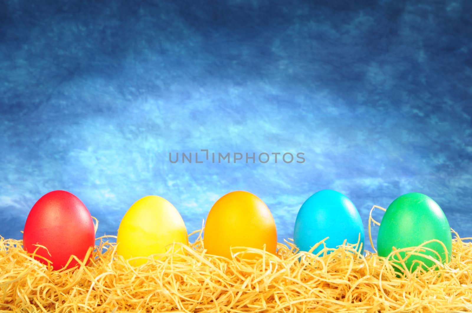 five painted eggs on a straw on a blue background