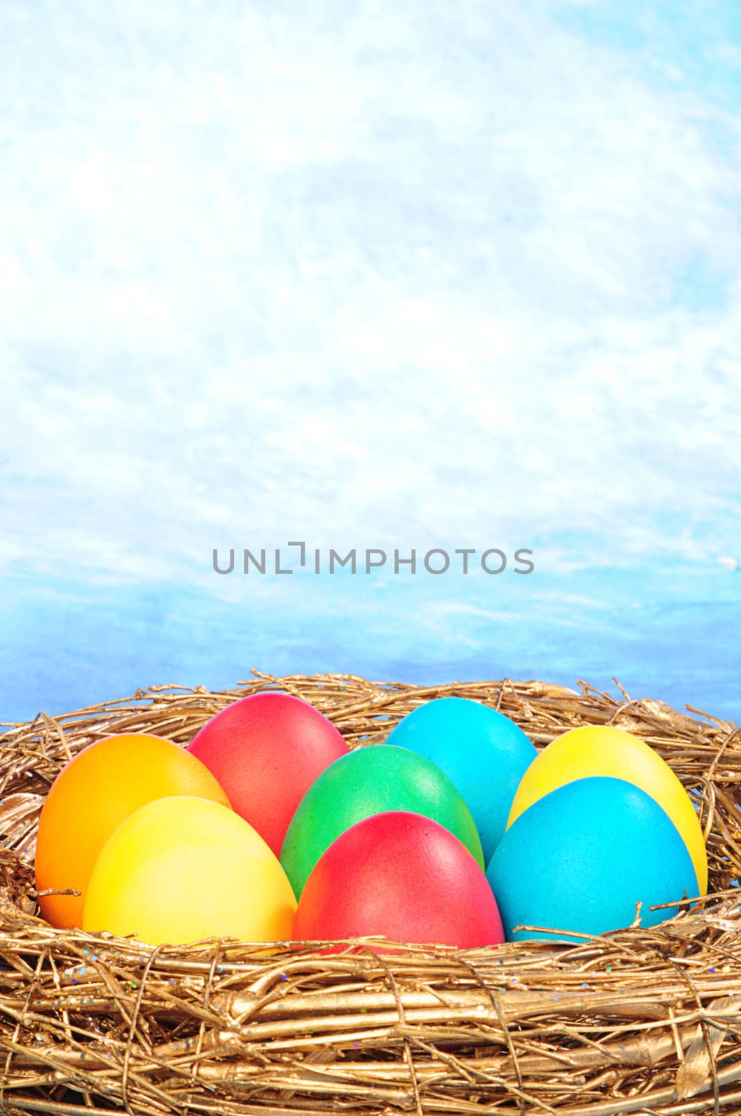 color eggs in a golden nest on blue sky background