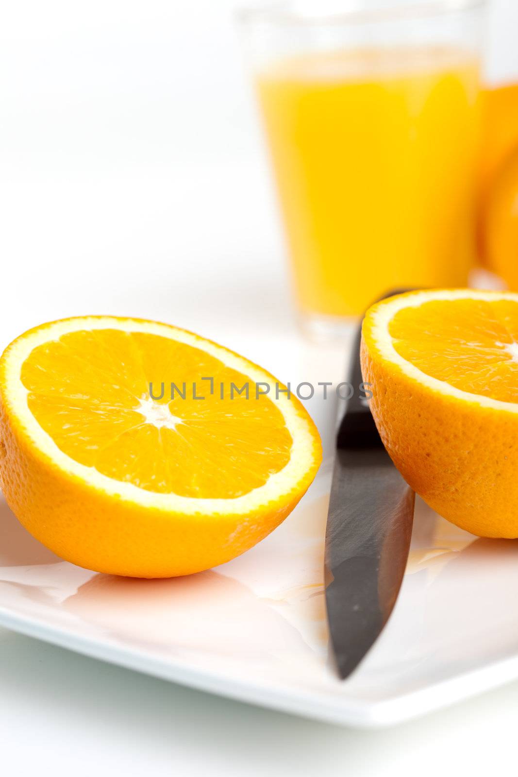 Orange cut into two halves with knife on a plate