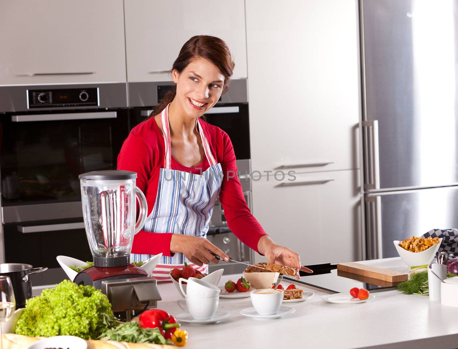 Brunette standing in the kitchen and dividing the cake