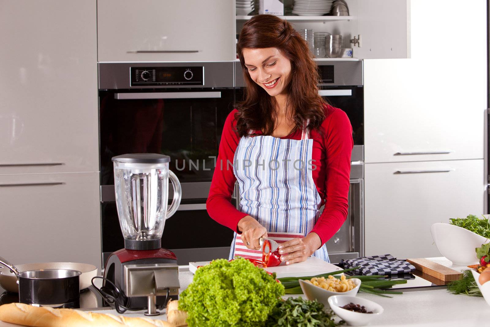 Beautiful brunette working in the kitchen cutting vegetables