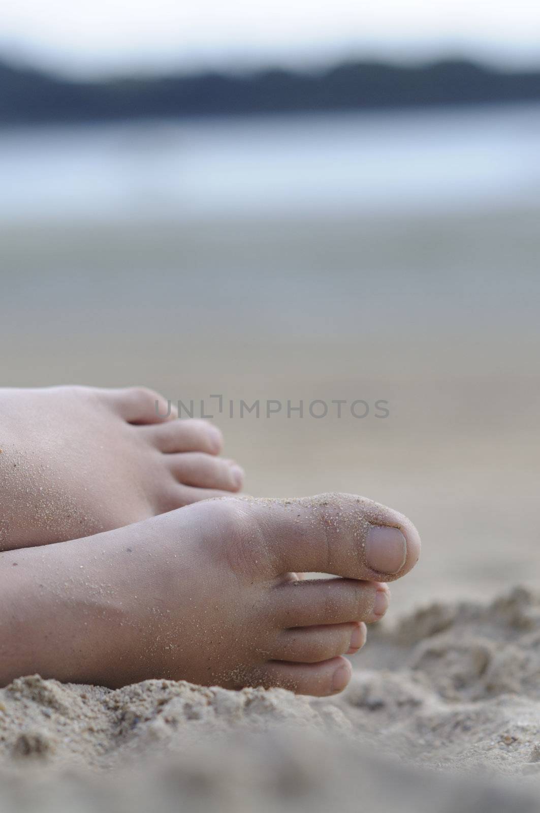 Shot of feet in the sand of woman relaxing at the beach.