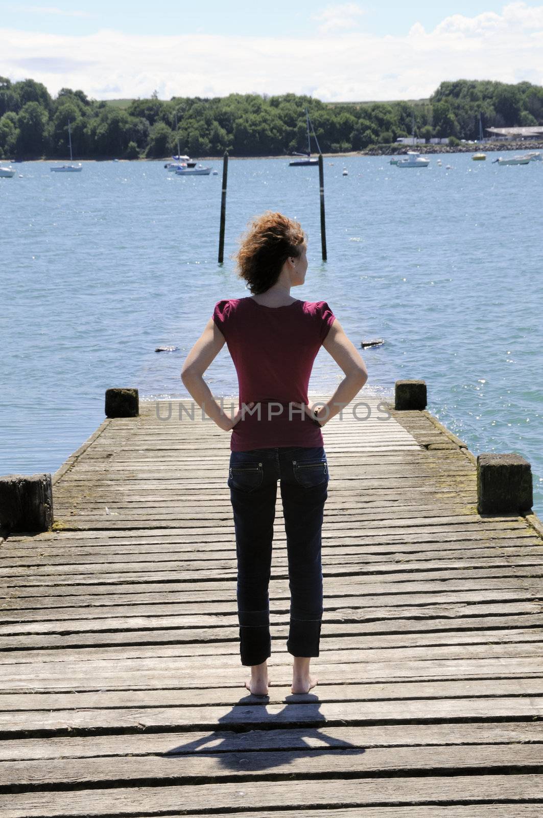 Girl standing on landing stage, watching the ocean.