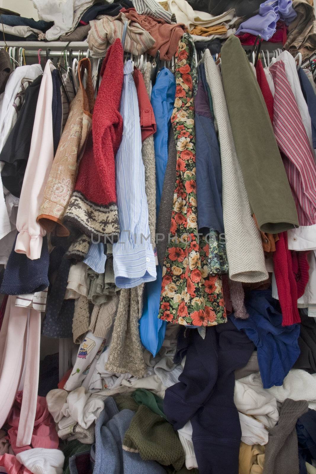 messy closet overfilled with colorful woman clothes on hangers and stuffed in any available space