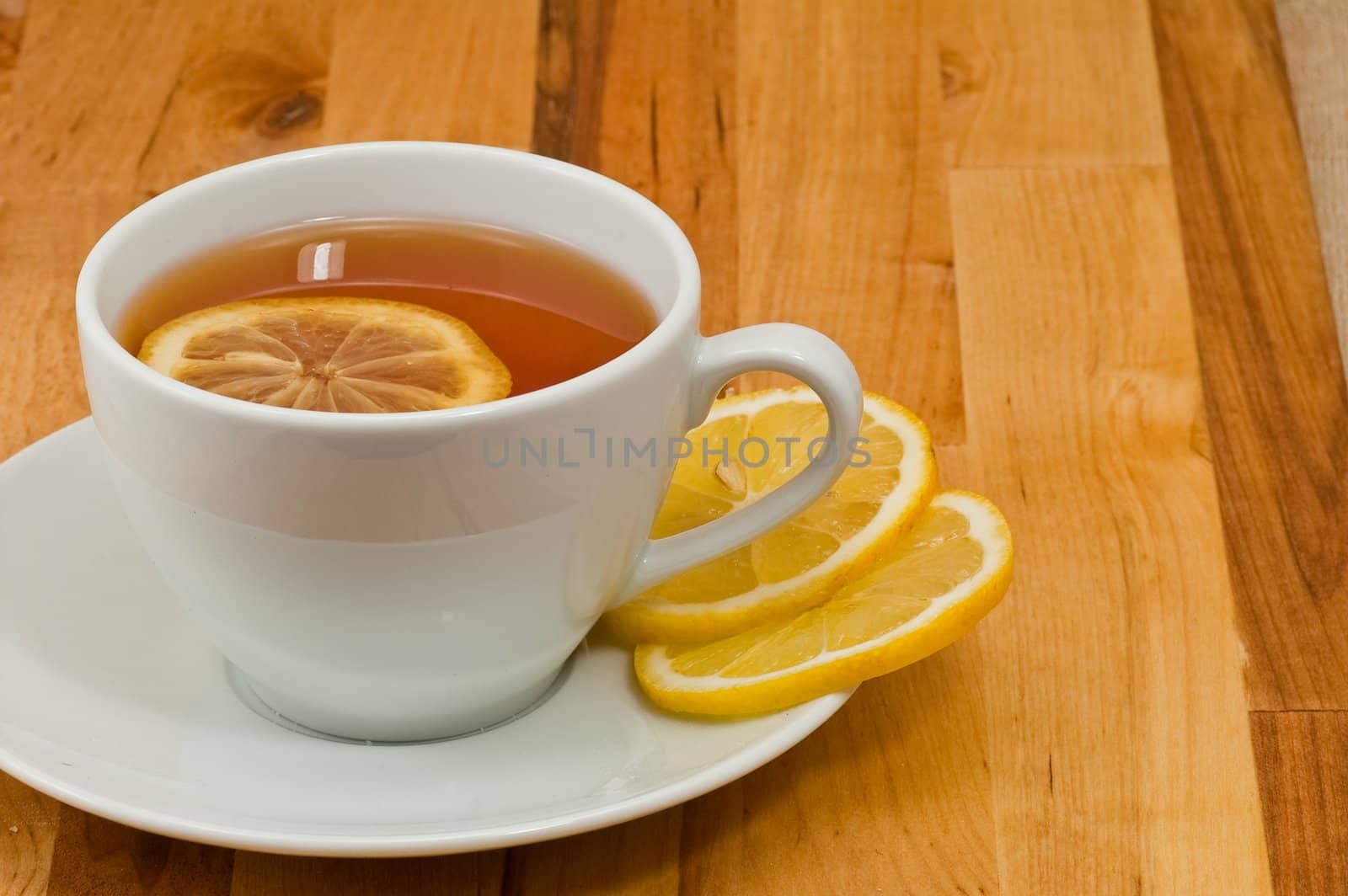 White porcelain cap of tea with sliced lemon on the wooden table