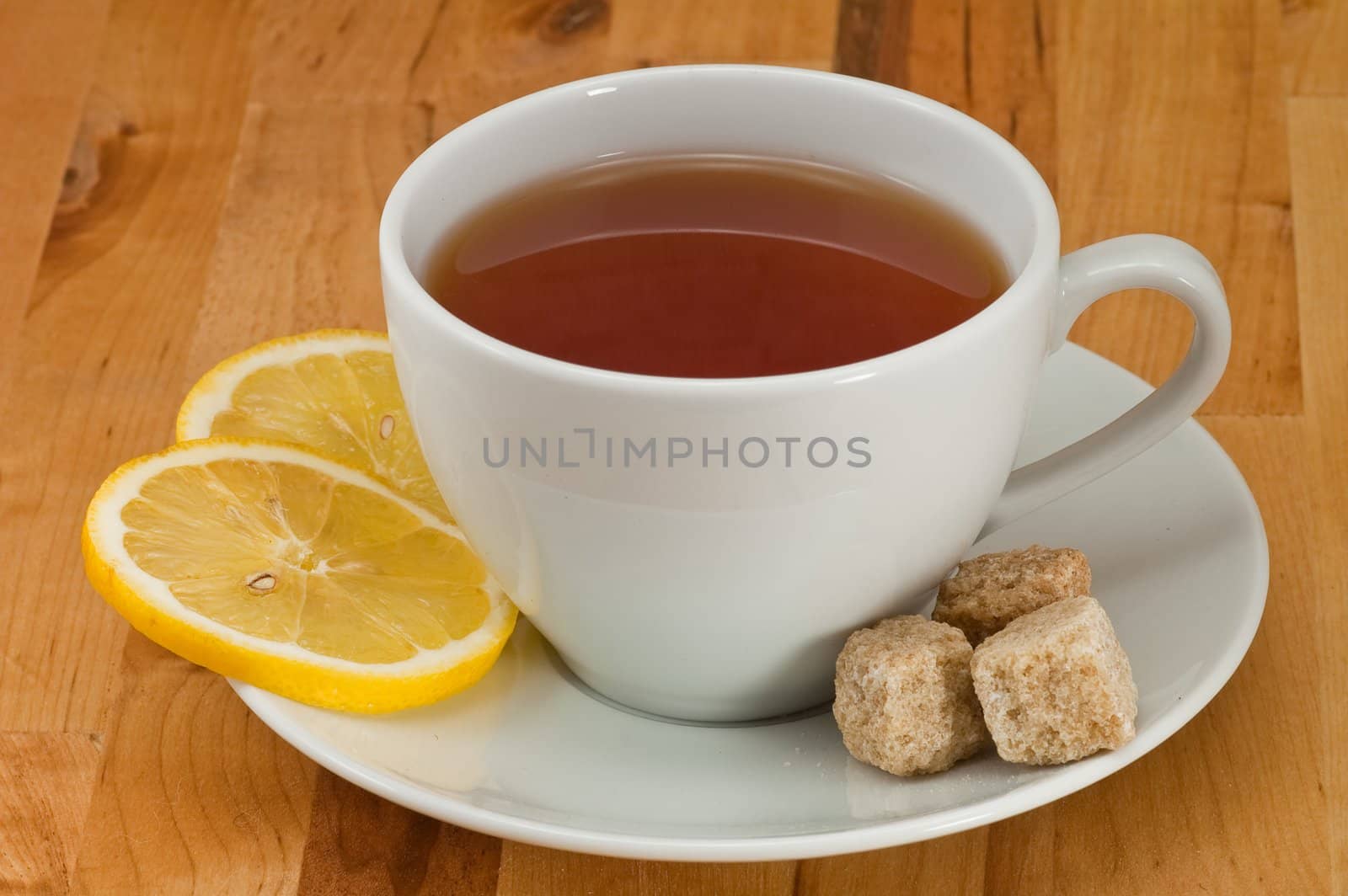 White porcelain cap of tea with sliced lemon and brown sugar on the wooden table