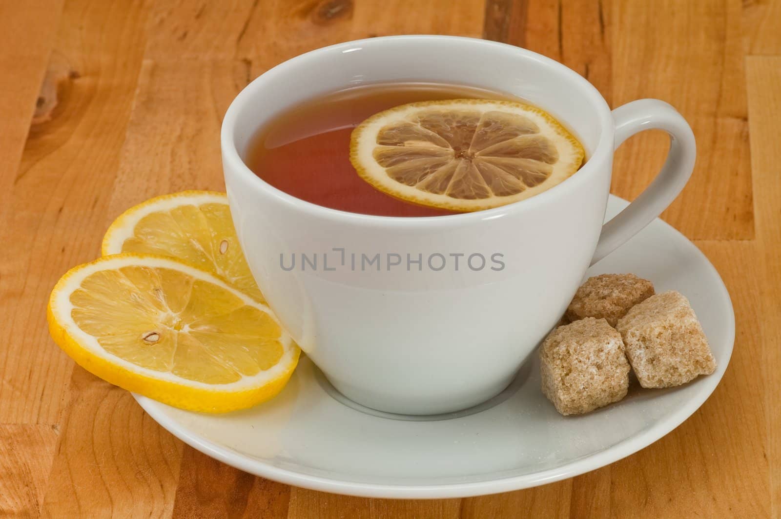 White porcelain cap of tea with sliced lemon and brown sugar on the wooden table