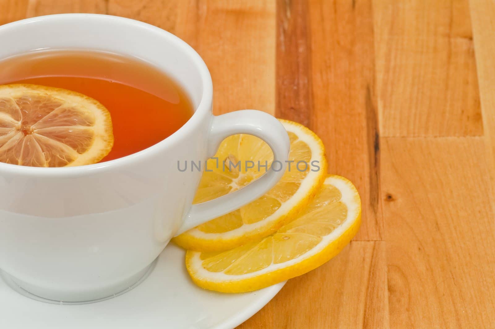 White porcelain cap of tea with sliced lemon on the wooden table