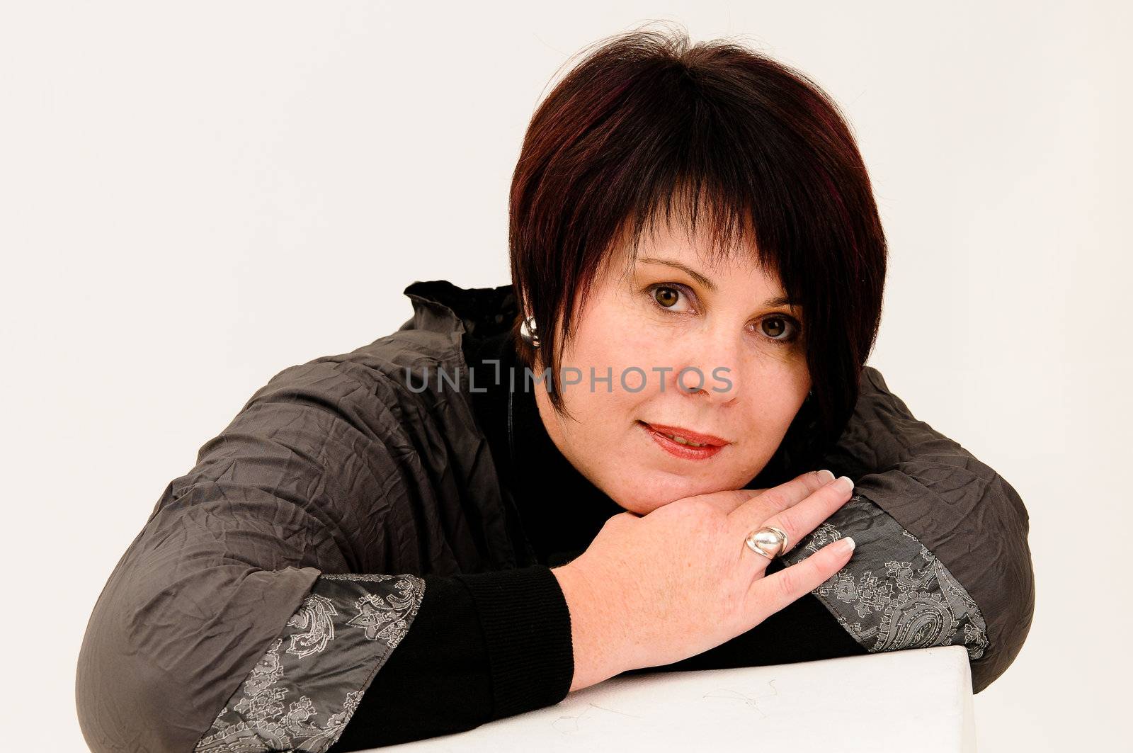 Beautiful attractive short haired mature woman with head leaning on hands whilst smiling