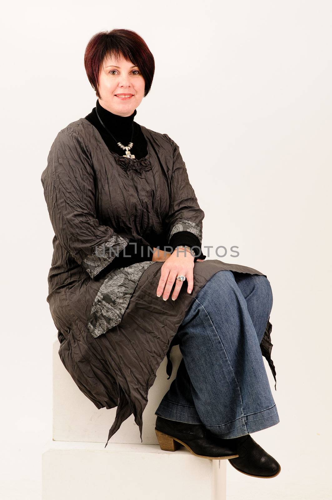 Beautiful attractive mature woman sitting in blue jeans and coat by Ansunette