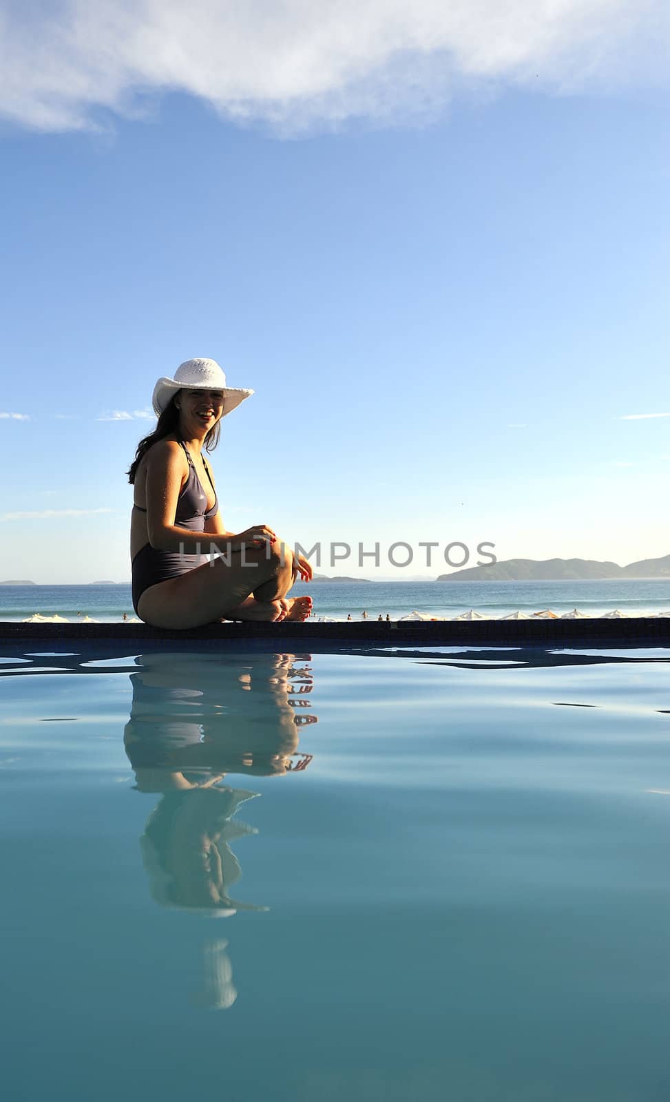 Woman relaxing on a swimming pool with a sea view
