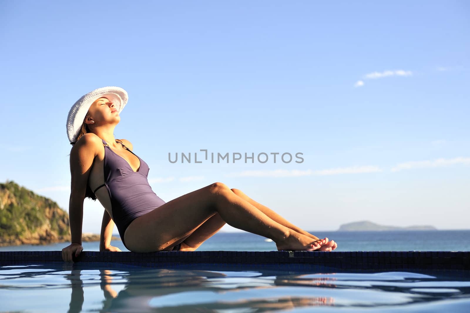 Woman relaxing on a swimming pool with a sea view
