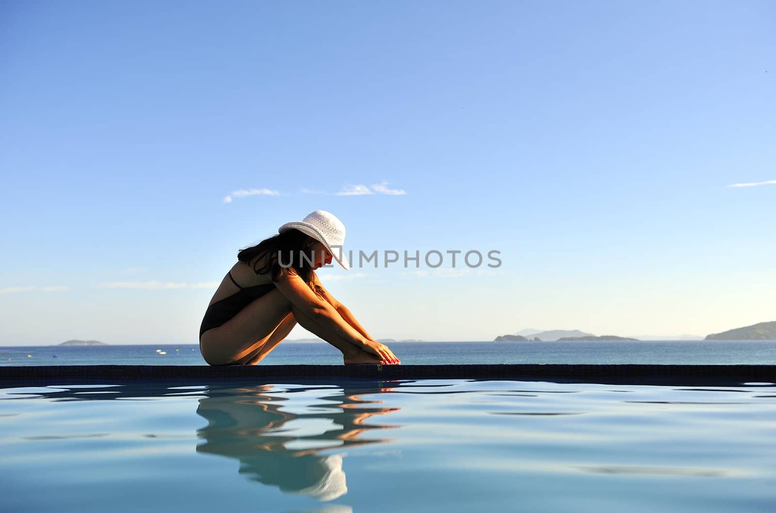 Woman relaxing on a swimming pool with a sea view
