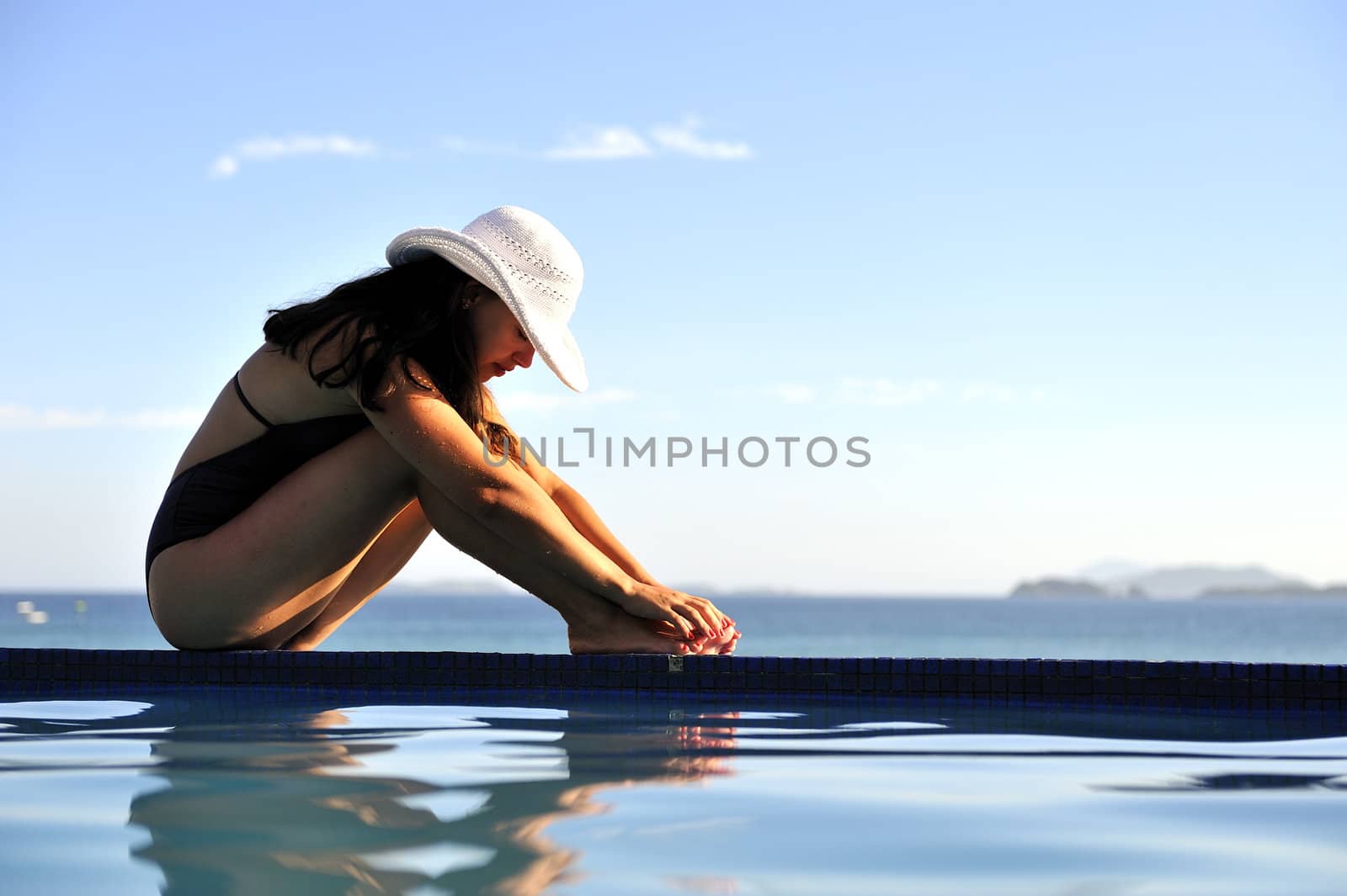 Woman relaxing on a swimming pool with a sea view
