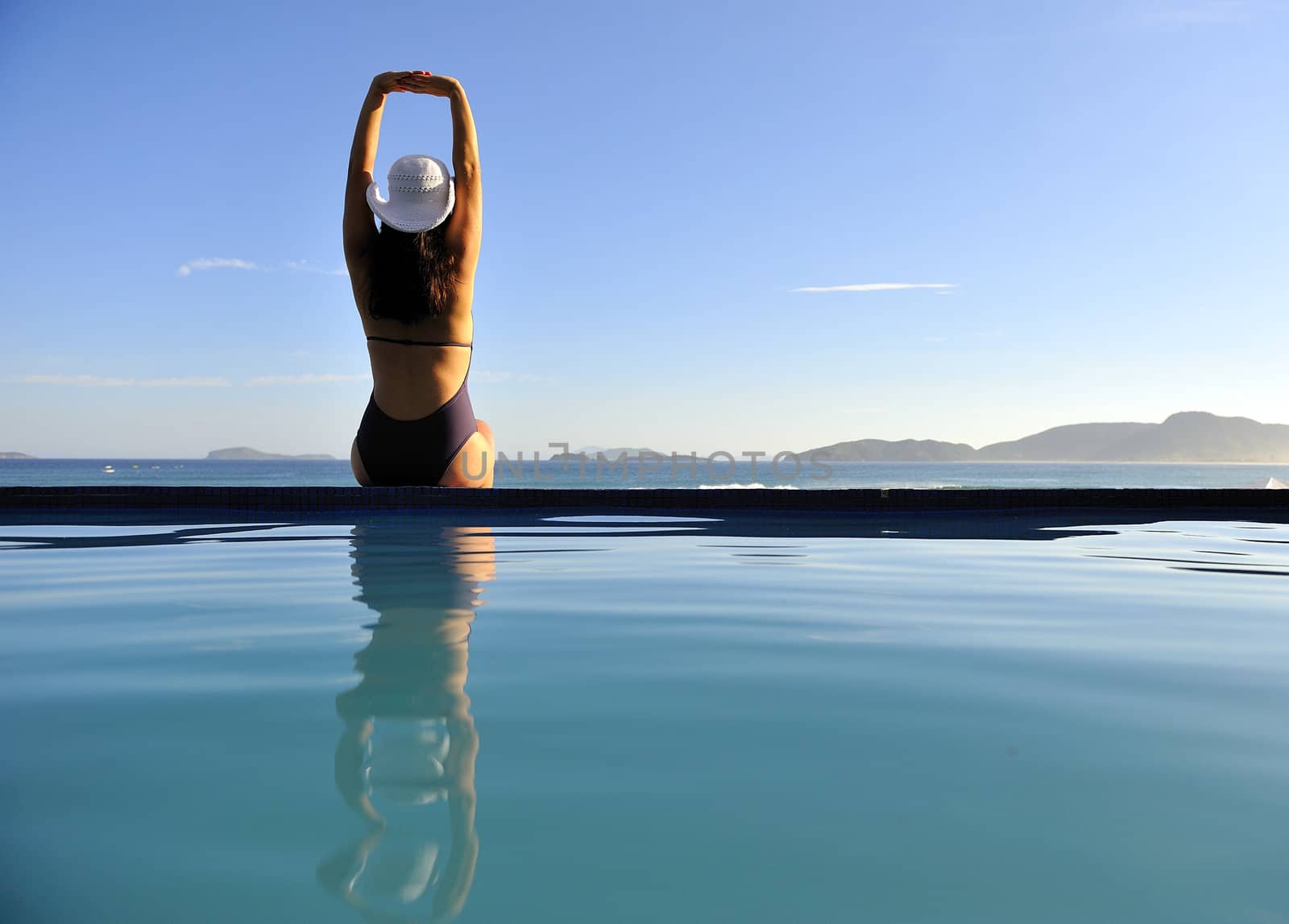 Woman relaxing on a swimming pool with a sea view
