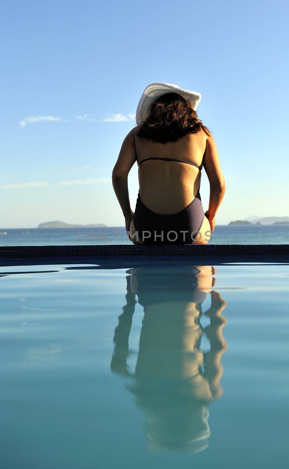 Woman relaxing on a swimming pool with a sea view
