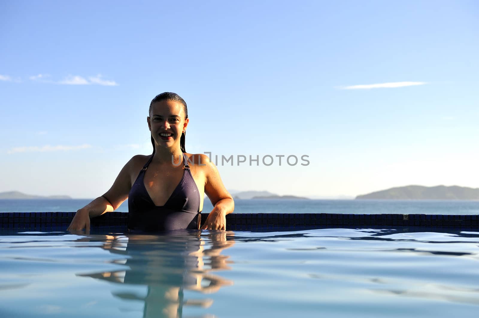 Woman relaxing on a swimming pool with a sea view
