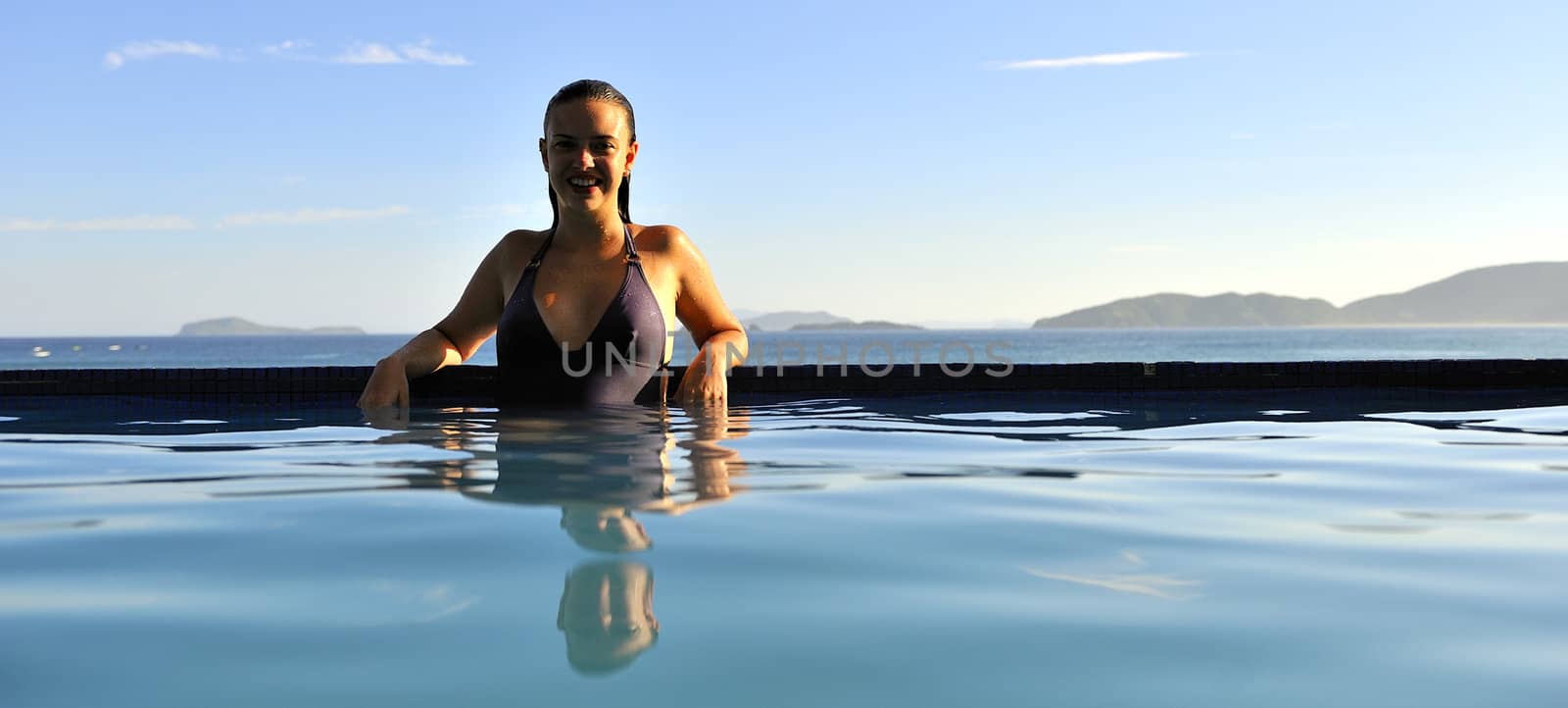 Woman relaxing on a swimming pool with a sea view
